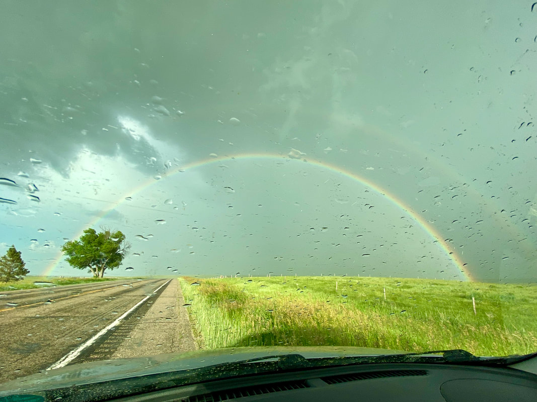 Double rainbow behind a raindrop speckled windshield